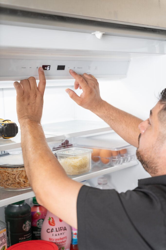 Person adjusting the temperature settings inside a refrigerator