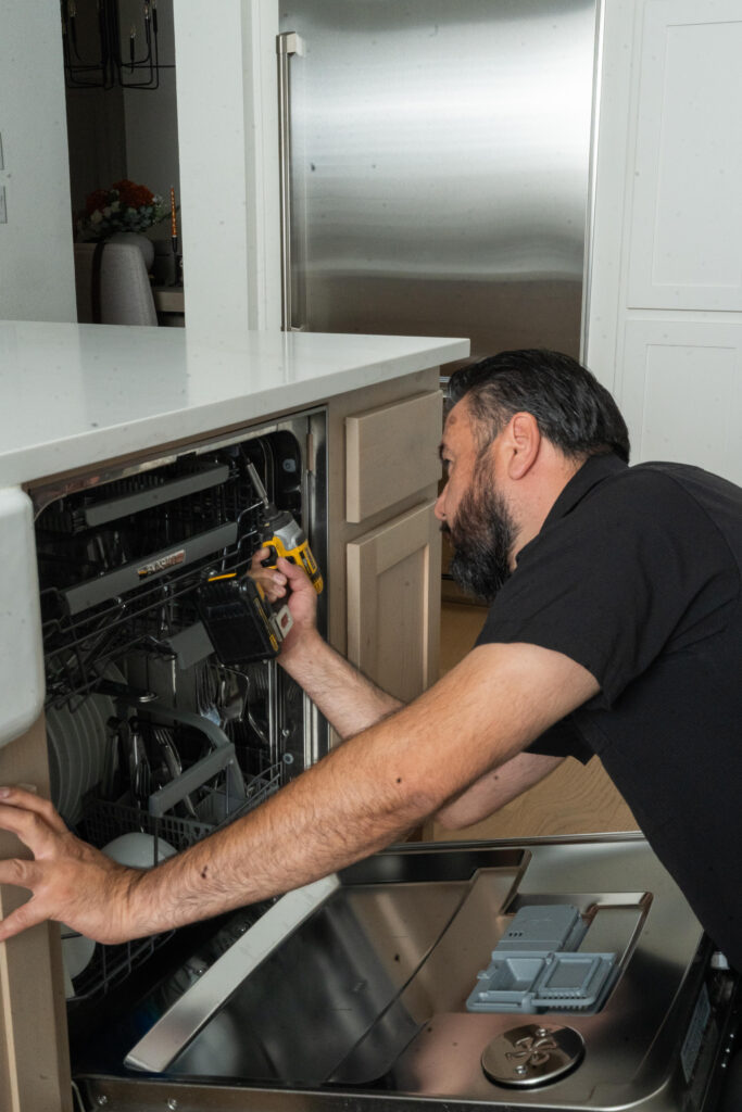 Man repairing a dishwasher in a modern kitchen setting