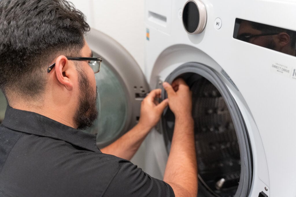 Man adjusting settings on a modern washing machine in a laundry room