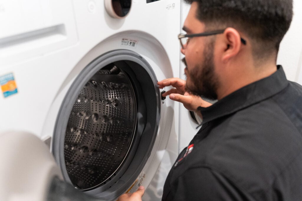 Man wearing glasses inspecting a washing machine drum