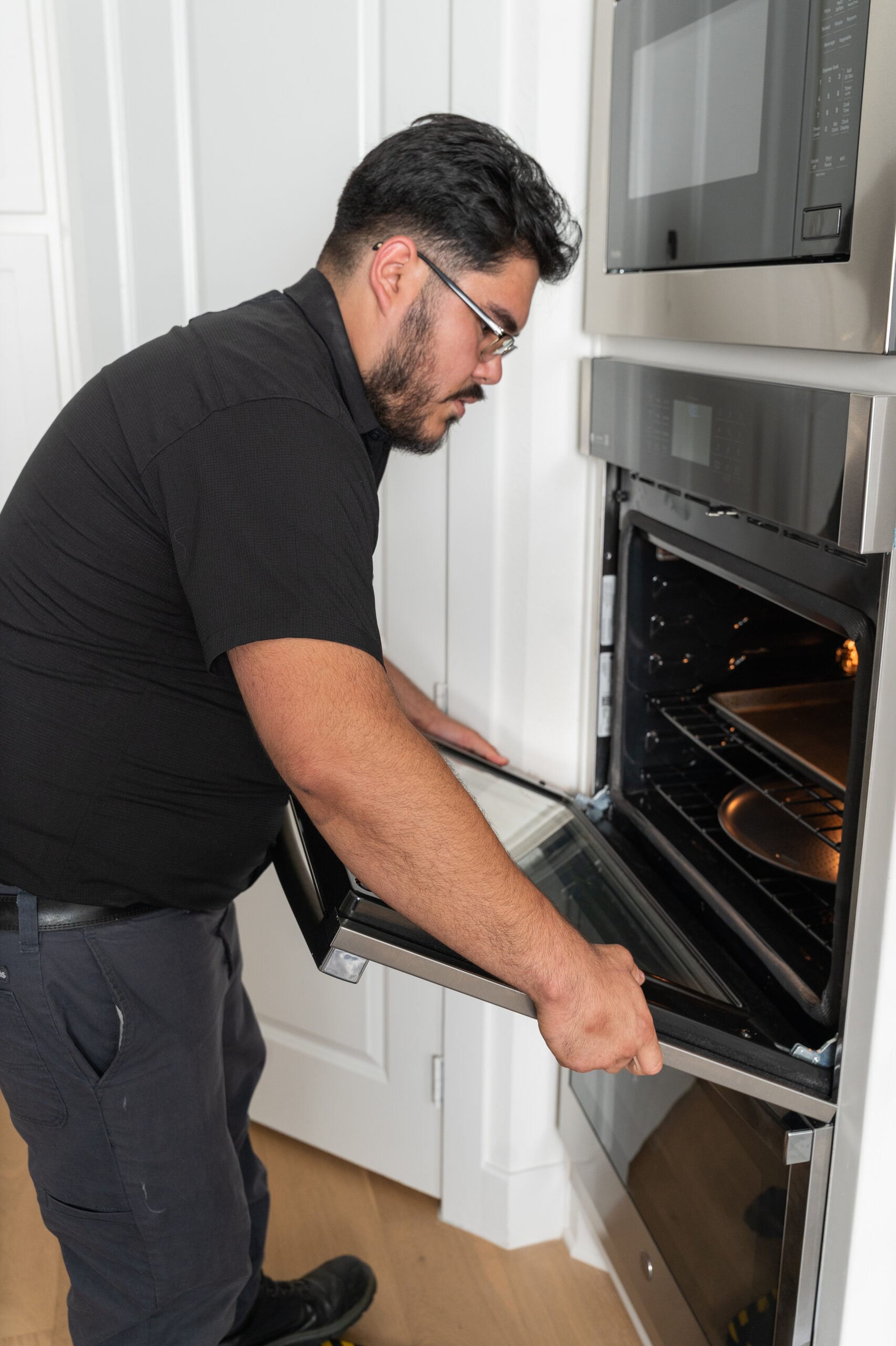 Action Appliance Repair technician repairing a wall oven
