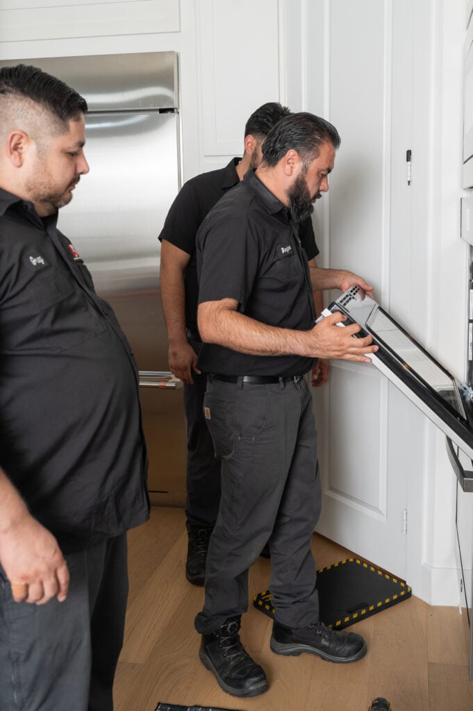 Technicians inspecting a wall oven