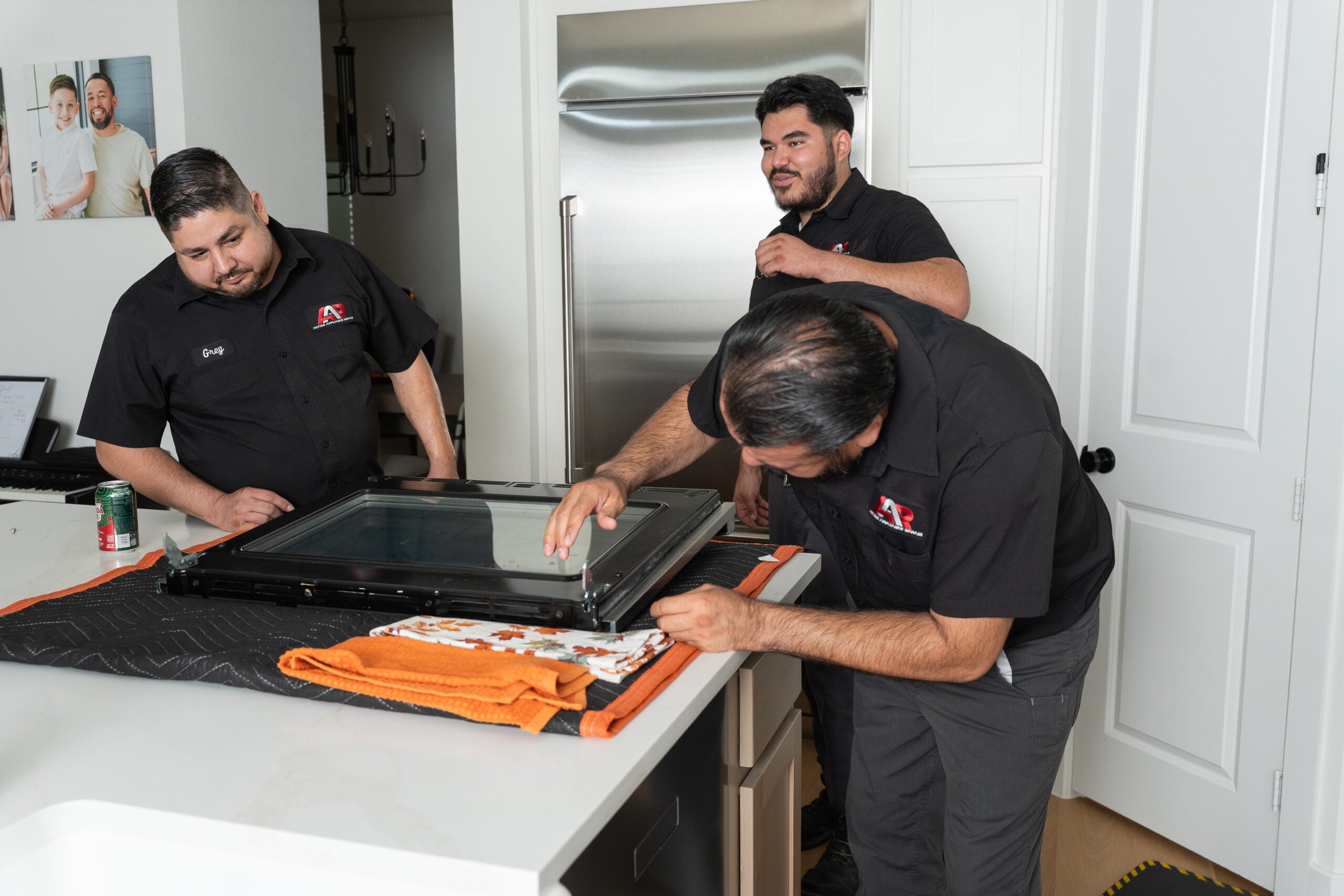 Technicians repairing an oven door on a kitchen counter