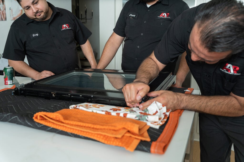 Technicians removing an oven door glass panel