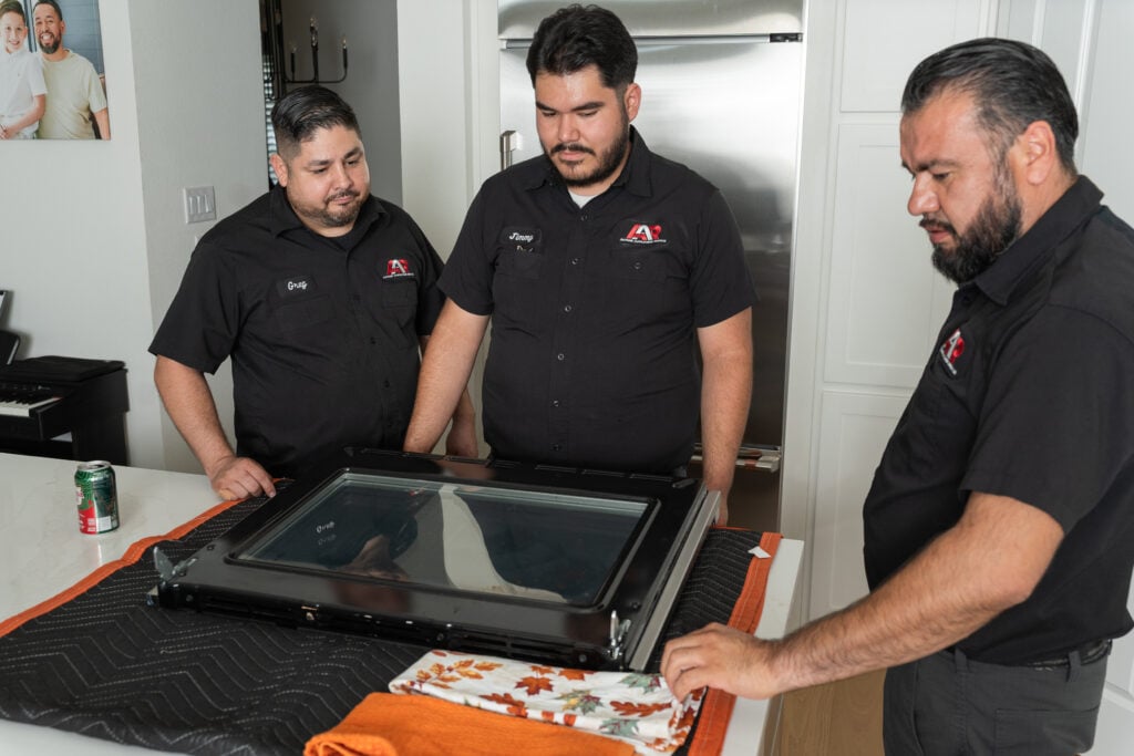 Technician inspecting an oven door during a repair