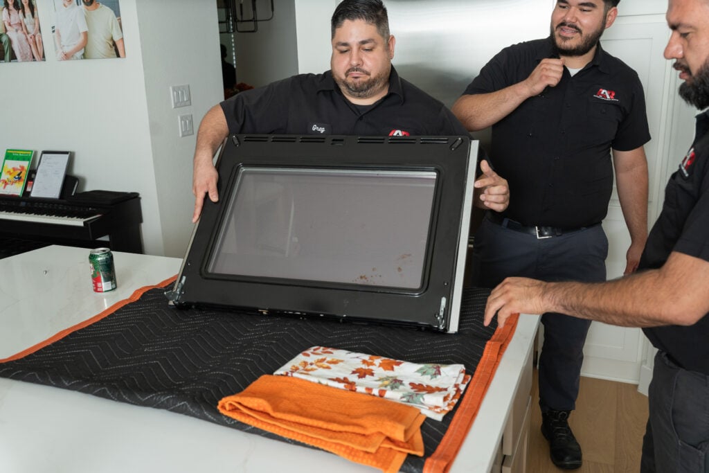 Action Appliance Repair technicians servicing a high-end oven