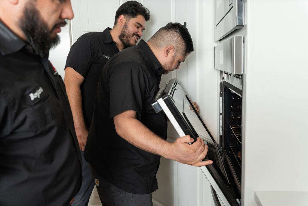 Technicians repairing a built-in wall oven
