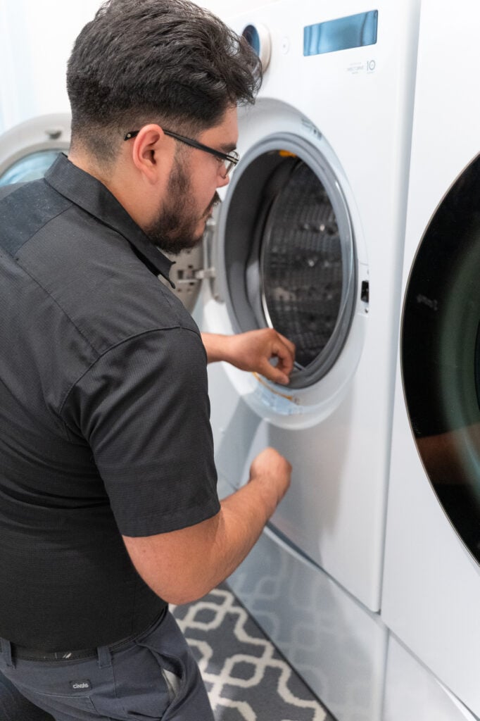 Technician working inside a front-load washer drum