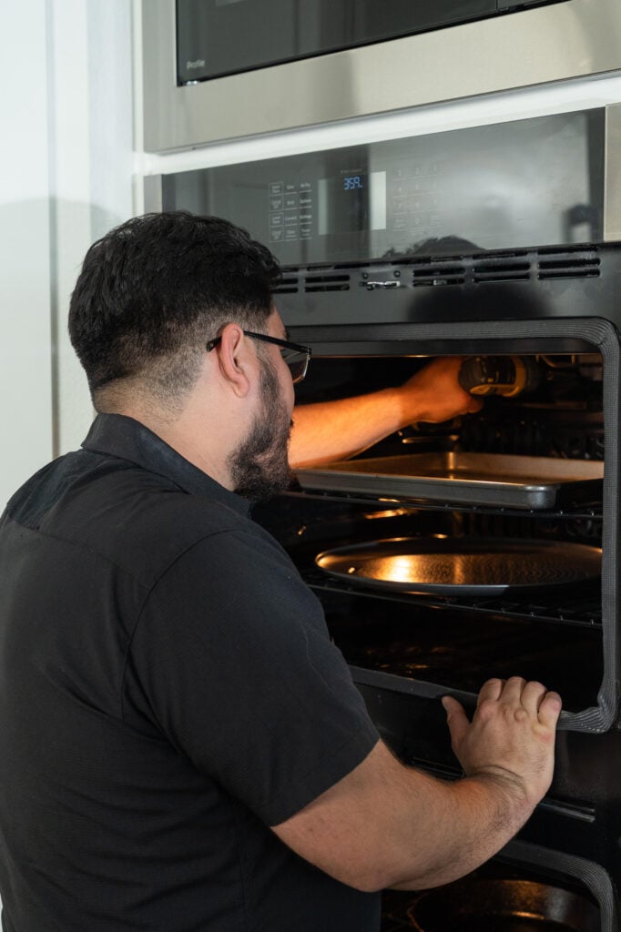 Man checking food in a modern oven with multiple trays